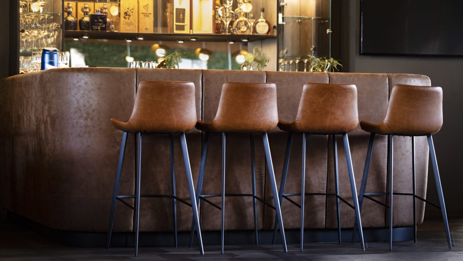 Forsthofgut 2 Exklusive Bar mit elegantem, abgerundetem Thekenbereich und hochwertigen Lederbarhockern. Die Barregale und das dezente Design schaffen eine luxuriöse Atmosphäre. FHE GASTRO liefert maßgeschneiderte Lösungen für Bars und Gastronomiebetriebe.