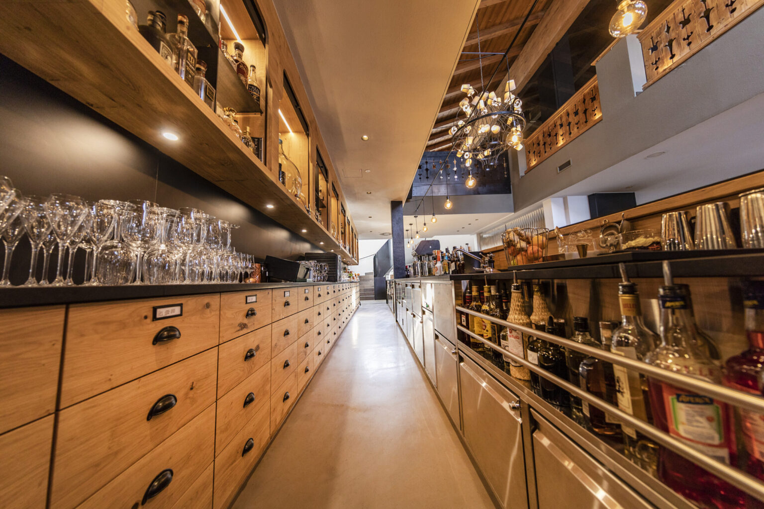 Forsthofgut 9 Gastronomische Theke von FHE GASTRO mit Regalen für Gläser und Spirituosen sowie modernen Küchengeräten und integrierten Kühlschränken. Das minimalistische Design kombiniert Funktionalität und Stil für Restaurants und Bars.