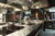 Edelstahl-Arbeitsfläche mit Induktionskochfeldern und modernen Kochgeräten, darunter Töpfe und ein Wasserhahn mit professionellem Design, ergänzt durch eine Dampfgarer-Station und einen Mixer