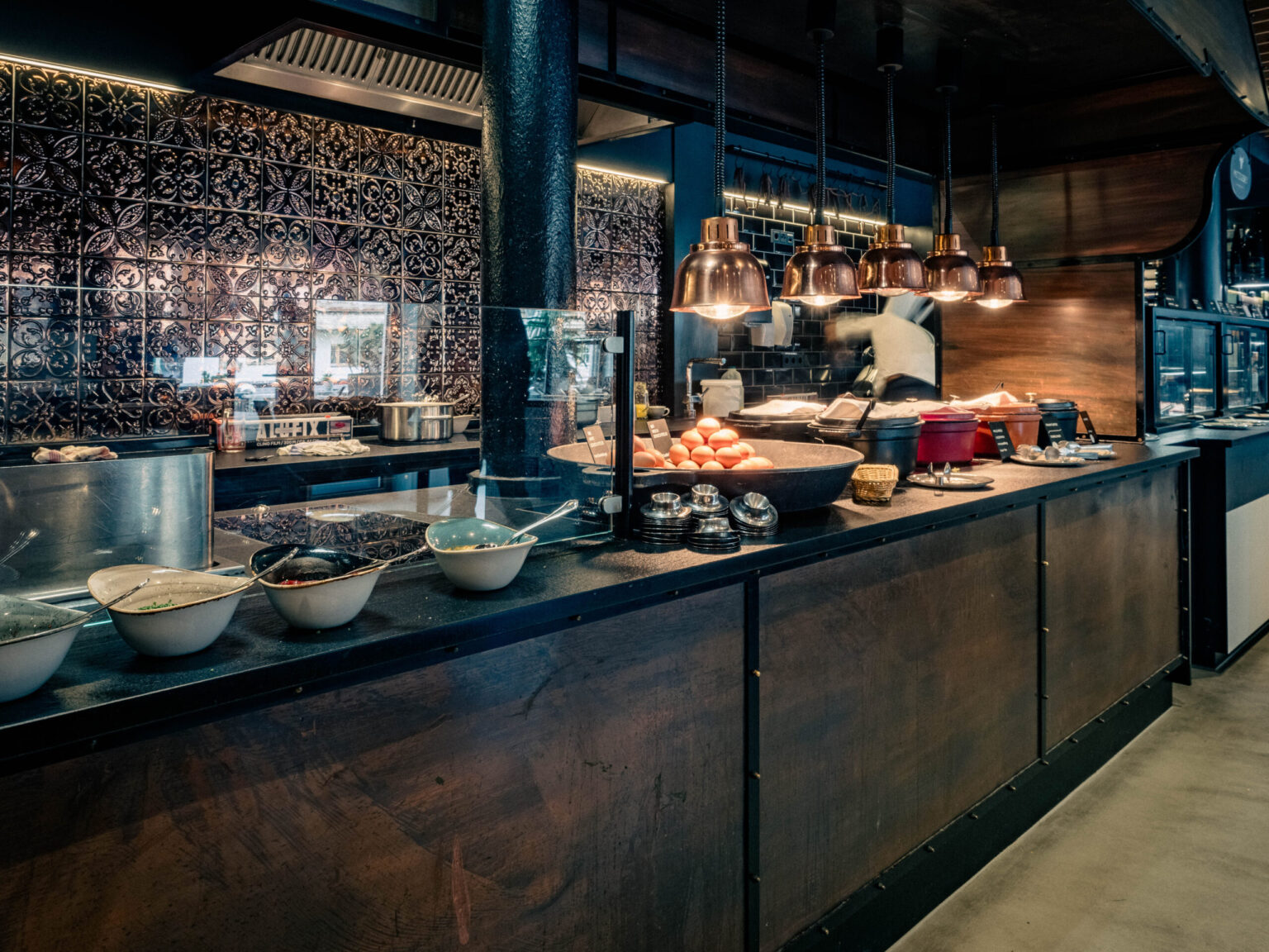 BUFFET_Forsthofgut-April_2024-232-HDR Küchenbereich eines Buffets mit eleganten Kupferlampen und einer Auswahl an frischen Zutaten. Diese maßgeschneiderte Buffettheke ist ein Beispiel für die hochwertigen Gastronomiemöbel von FHE GASTRO, die sowohl funktional als auch ästhetisch ansprechend sind.