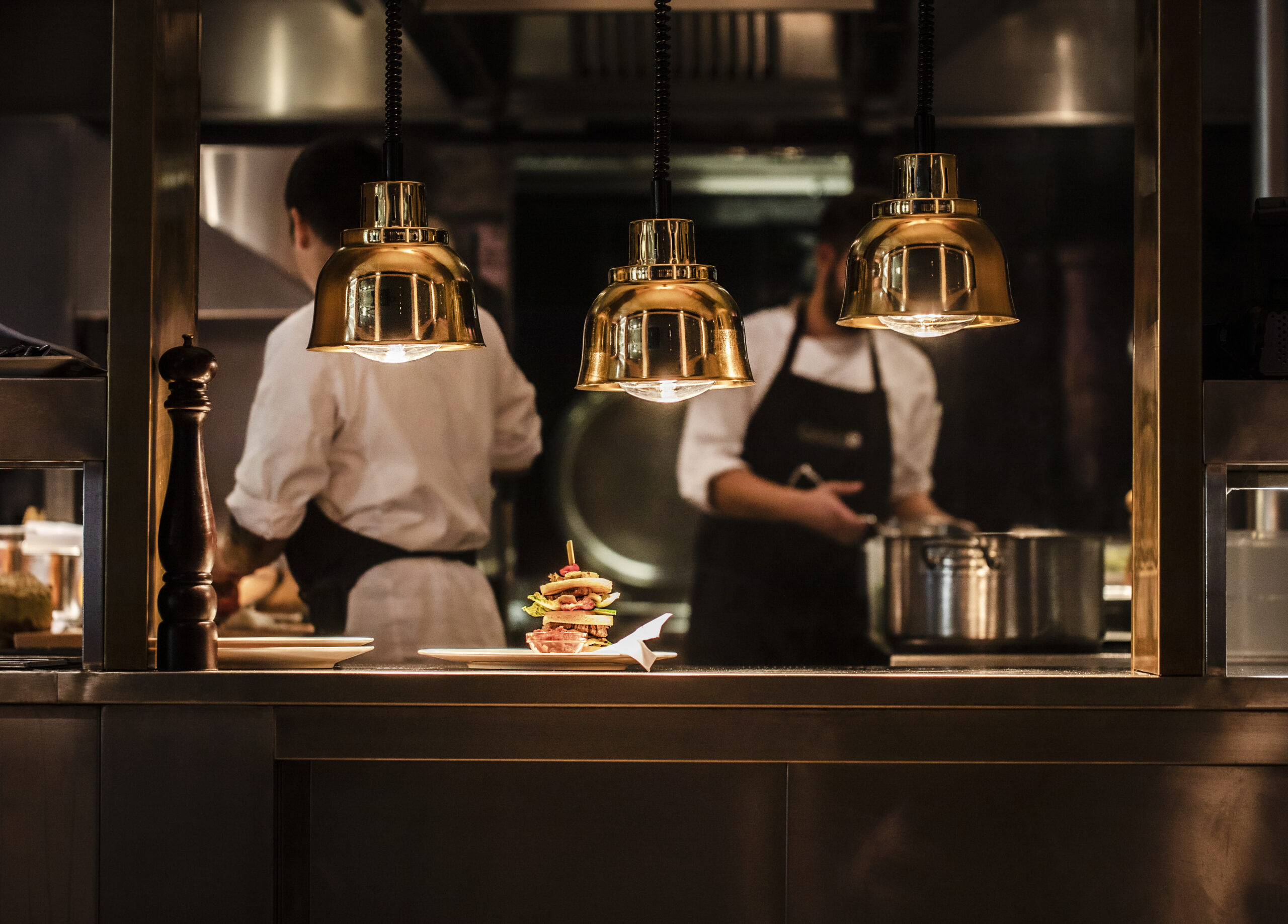 Gams Bezau 19 (15) FHE GASTRO Profi-Küchenausstattung in einer offenen Küche mit leistungsstarken Kochfeldern und zuverlässigen Wärmelampen für effizientes Arbeiten und optimale Speisenpräsentation.