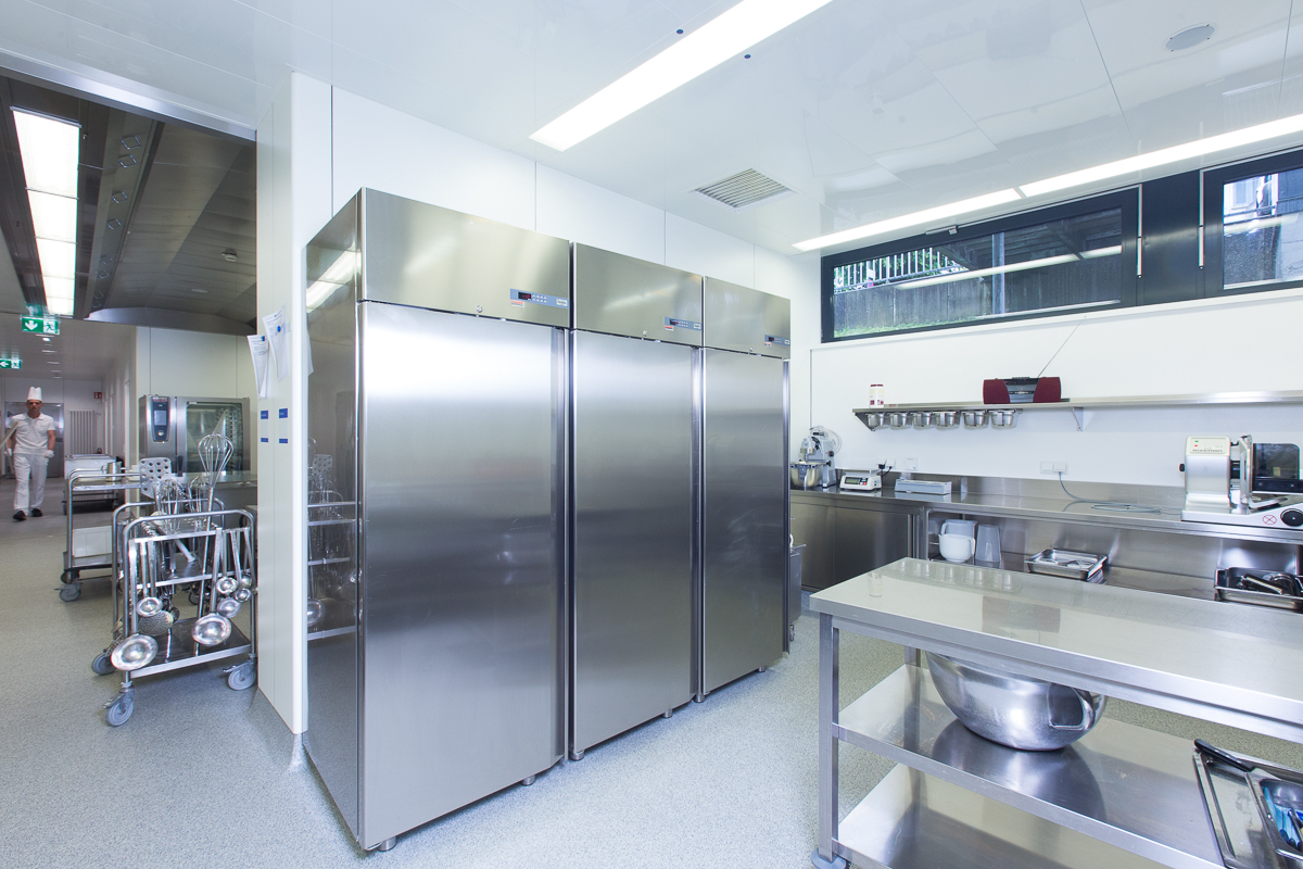 Ein gut ausgestatteter Bereich einer Gastronomieküche mit hochwertigen Edelstahl-Kühlgeräten, Arbeitsflächen und professionellen Geräten von FHE GASTRO. Diese Küche bietet alle nötigen Ressourcen für eine effiziente und hygienische Zubereitung von Speisen.