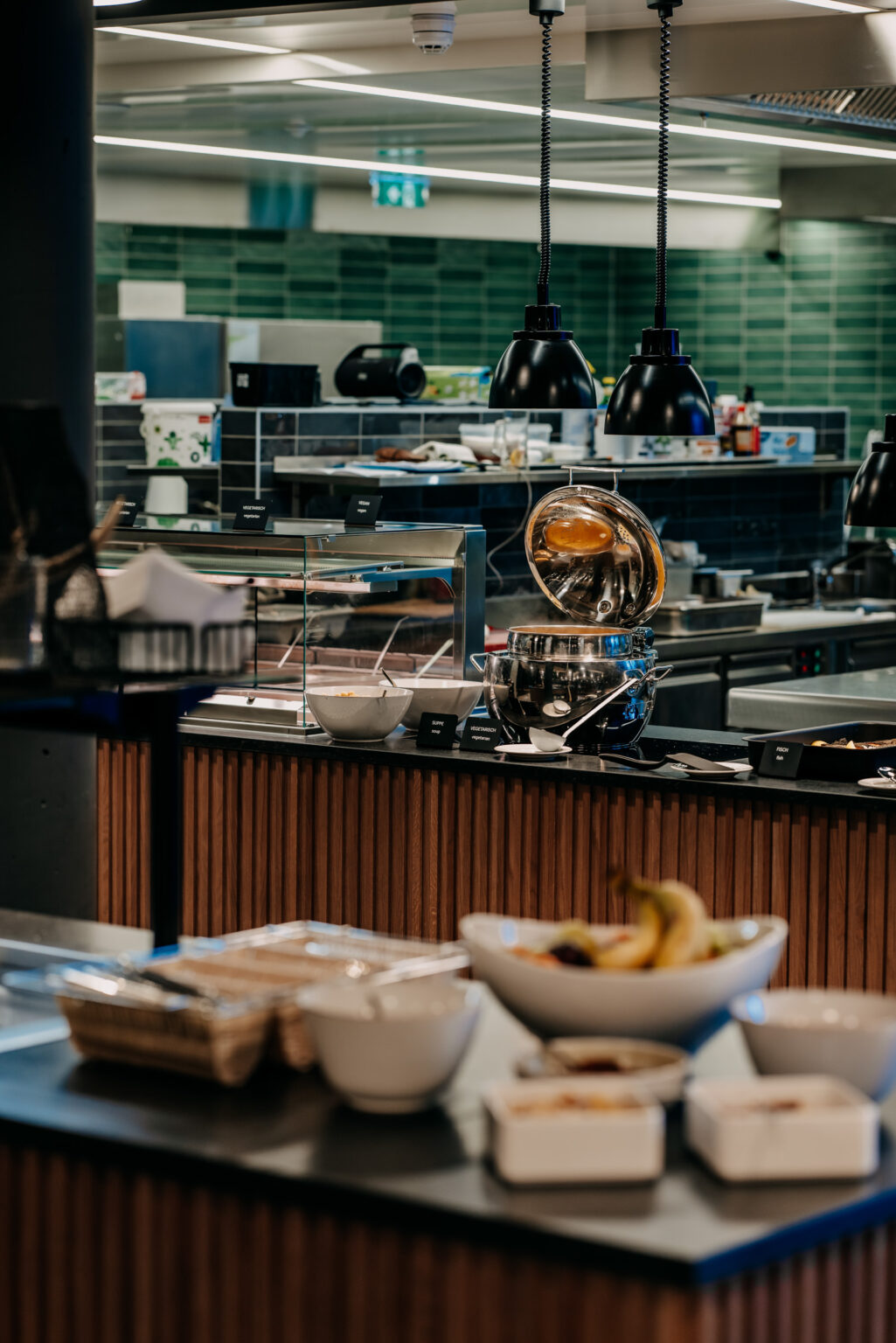 231226_Campus_forsthofgut-234 Professionelle Gastronomie-Theke mit einer breiten Auswahl an frischen Beilagen und Salaten. Die moderne Ausstattung und die elegante Beleuchtung sorgen für eine ansprechende Präsentation und eine angenehme Atmosphäre. FHE GASTRO bietet maßgeschneiderte Thekenlösungen für den Gastrobereich, die Funktionalität und Design vereinen.