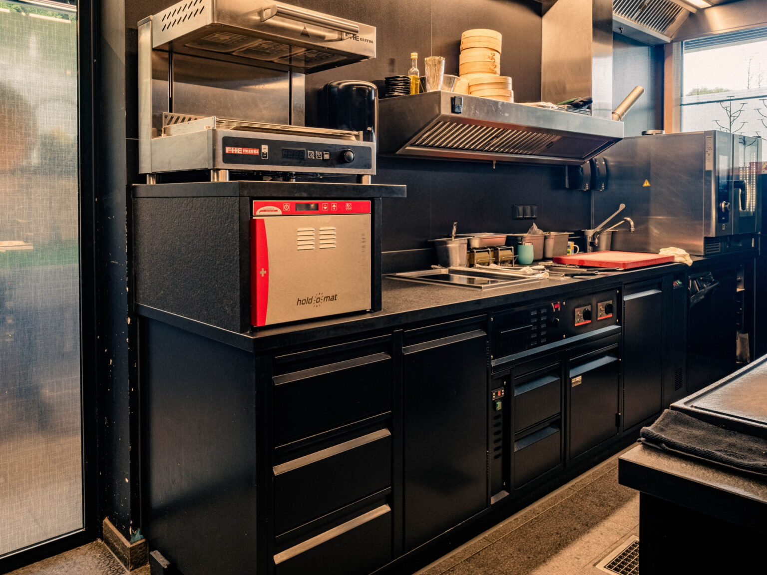 MIZUMI_Forsthofgut-April_2024-528-HDR Gut organisierte FHE GASTRO Küche mit modernen Geräten, einschließlich Wärmeschrank und robusten Kochstationen.